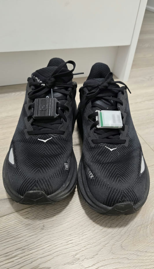 A pair of black running shoes with a Mylz tag clipped to each set of laces